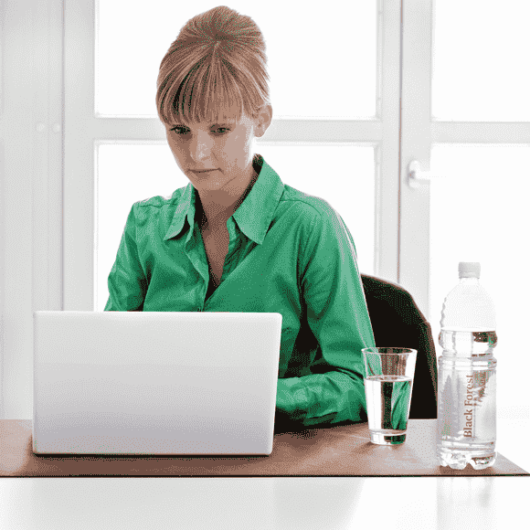 Junge Frau am Laptop trinkt Black Forest still