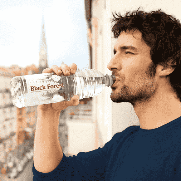 Junger Mann trinkt aus Black Forest Flasche